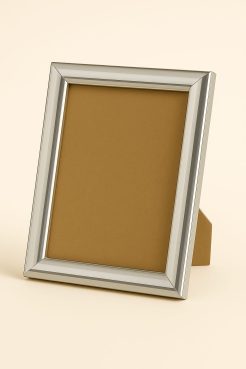 Portafoto color plata brillo, modelo 196-027. Fabricado en madera de pino finger forrada en aluminio con acabado lacado de alto brillo. Su diseño moderno y elegante, con perfil redondeado y superficie espejada, aporta luminosidad y sofisticación, ideal para enmarcar fotografías o láminas en espacios contemporáneos, oficinas o decoraciones minimalistas.