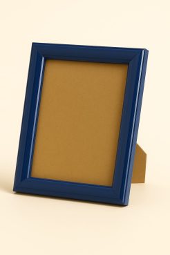 Portafoto color azul brillo, modelo 196-075. Fabricado en madera de pino finger forrada en aluminio con acabado lacado de alto brillo. Su diseño moderno y perfil redondeado aportan un toque de color y elegancia, ideal para enmarcar fotografías, láminas o recuerdos en espacios contemporáneos, juveniles o marinos.