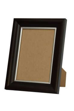 Portafoto nogal con filo plata modelo 367-194. Fabricado en madera de pino finger con un acabado en tono nogal oscuro y un delicado filo plateado. Su combinación de madera cálida y brillo metálico crea un efecto elegante y actual, ideal para realzar fotografías, retratos o láminas decorativas. Perfecto para ambientes modernos, clásicos o de estilo contemporáneo.