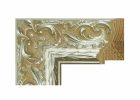 Marco de madera labrada con acabado plata, decorado con relieves ornamentales de inspiración clásica y fondo en tono cálido, con textura detallada y aspecto elegante.